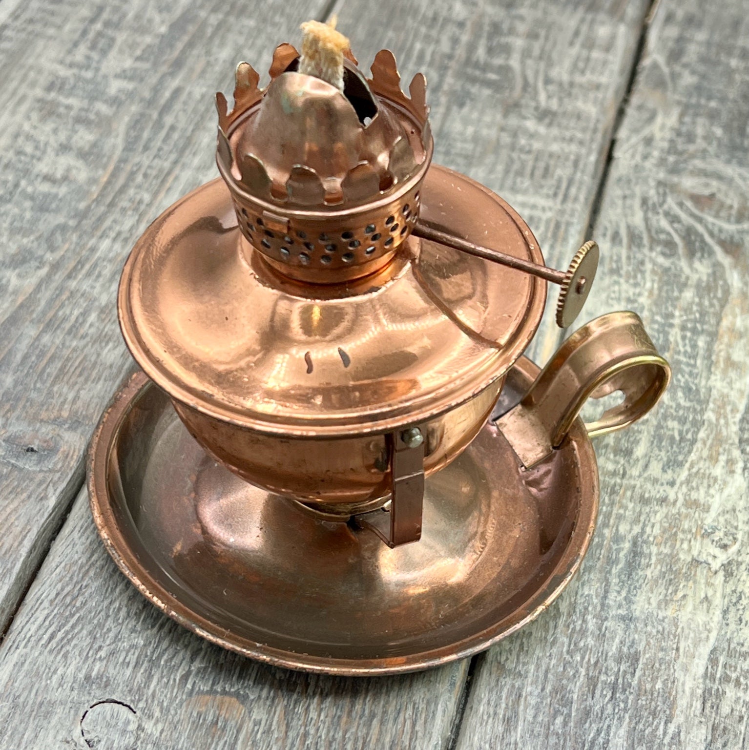 A vintage copper miniature chamber oil lamp featuring a round dish saucer base with a finger loop handle and a crown burner gallery with cotton wick. - Photo 1