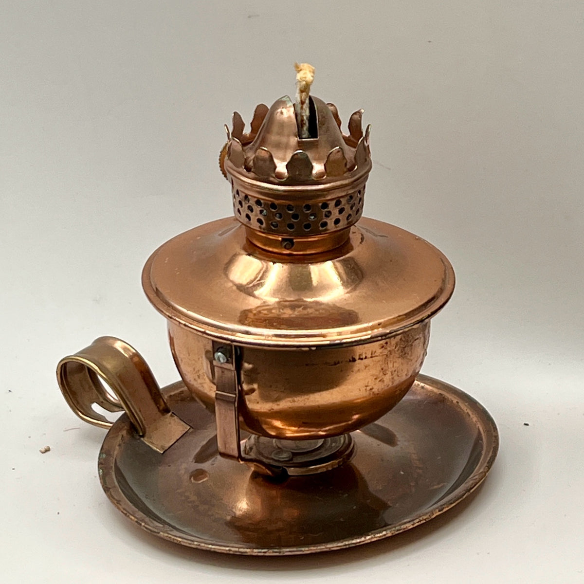 A vintage copper miniature chamber oil lamp featuring a round dish saucer base with a finger loop handle and a crown burner gallery with cotton wick. - Photo 2