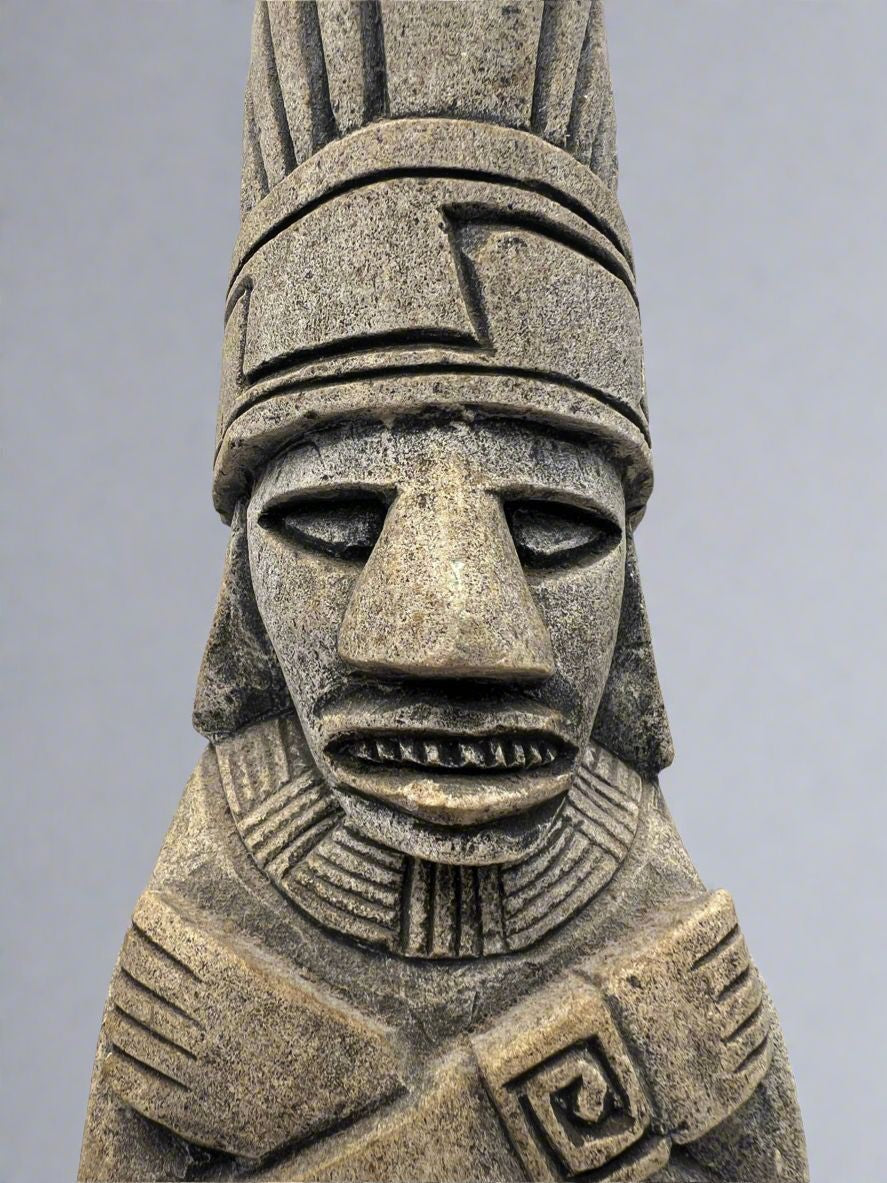 A carved gray stone bookend depicting a seated Aztec or Mesoamerican figure wearing a feathered headdress with incised geometric patterns on the base. - Photo 2