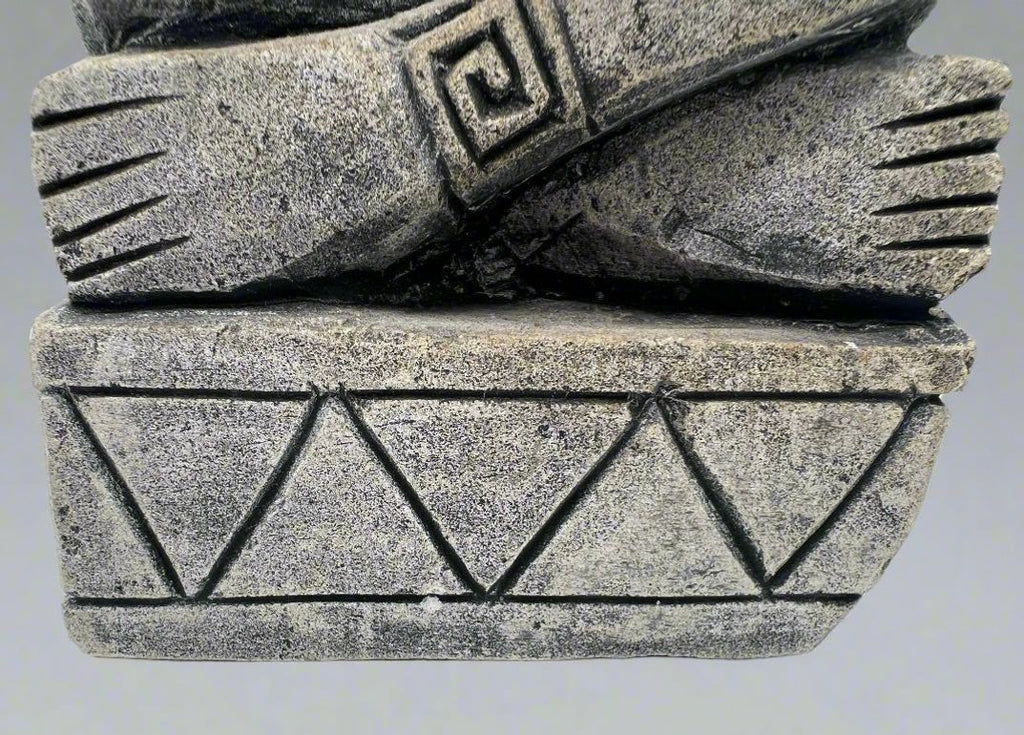 A carved gray stone bookend depicting a seated Aztec or Mesoamerican figure wearing a feathered headdress with incised geometric patterns on the base. - Photo 5