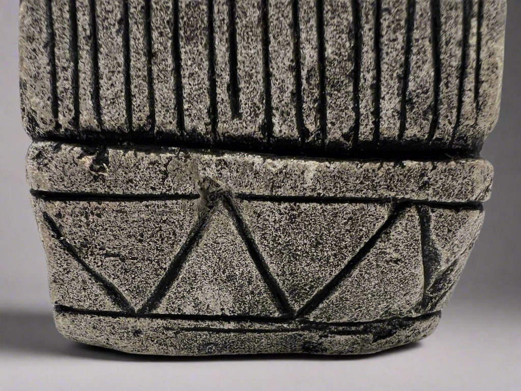 A carved gray stone bookend depicting a seated Aztec or Mesoamerican figure wearing a feathered headdress with incised geometric patterns on the base. - Photo 8