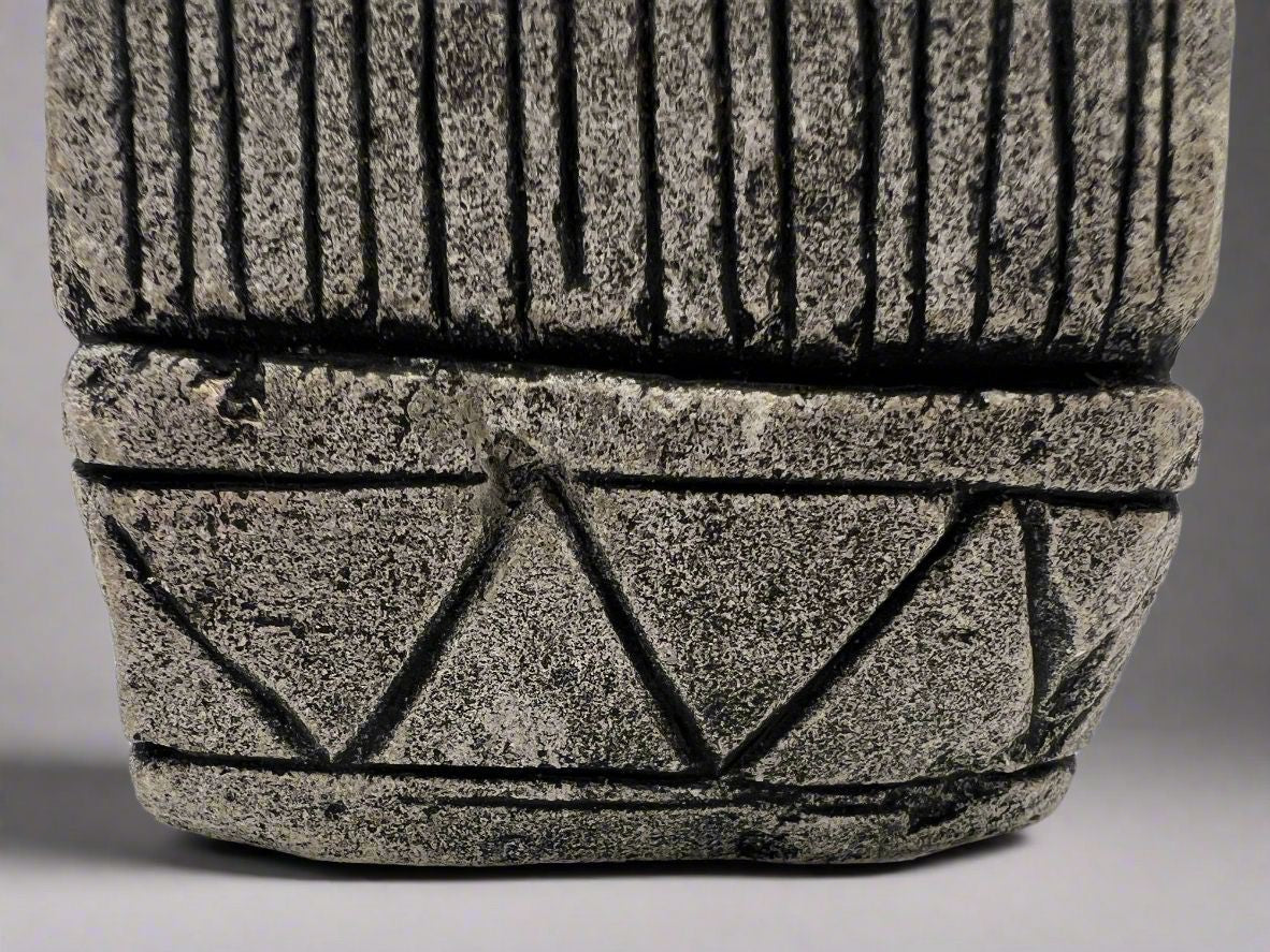 A carved gray stone bookend depicting a seated Aztec or Mesoamerican figure wearing a feathered headdress with incised geometric patterns on the base. - Photo 8