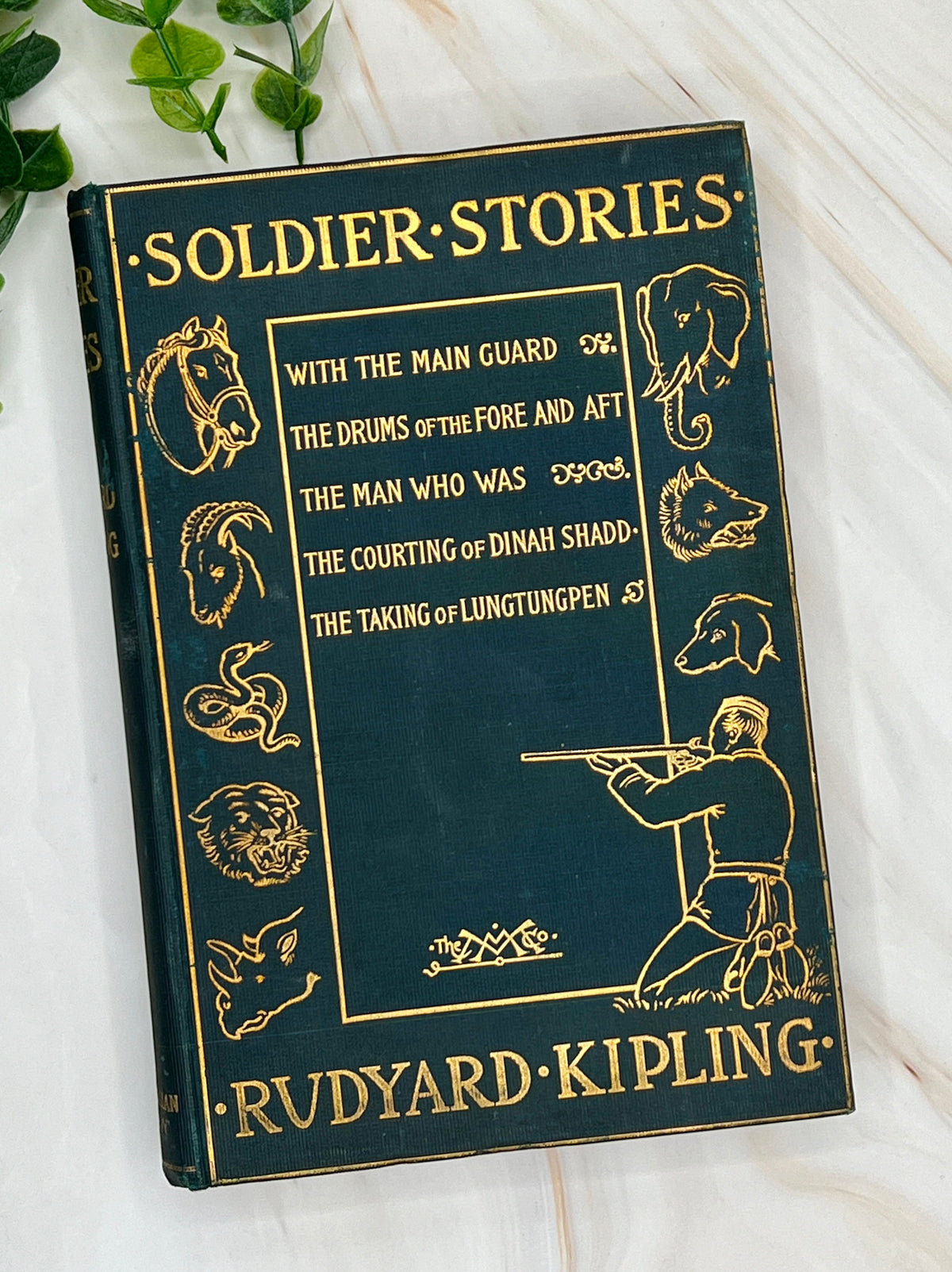 Dark green cloth hardcover book titled Soldier Stories by Rudyard Kipling featuring elaborate gilt embossed lettering, framed story titles, and wildlife illustrations. - Photo 1