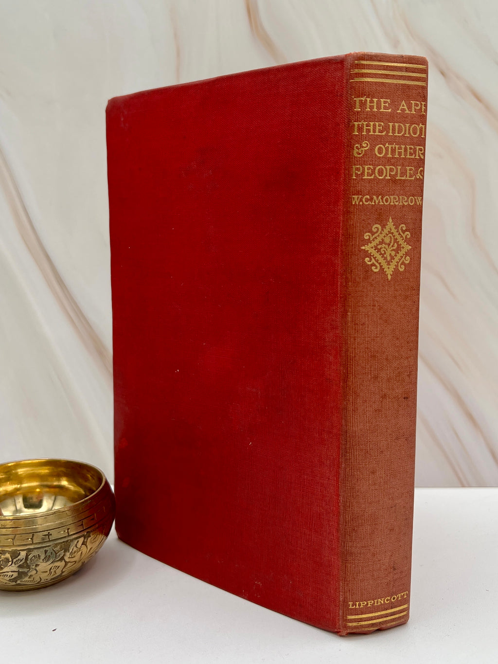 Antique red cloth hardcover book titled The Ape, the Idiot & Other People by W. C. Morrow, featuring an ornate gilt-stamped mythical dragon and gold lettering. - Photo 3