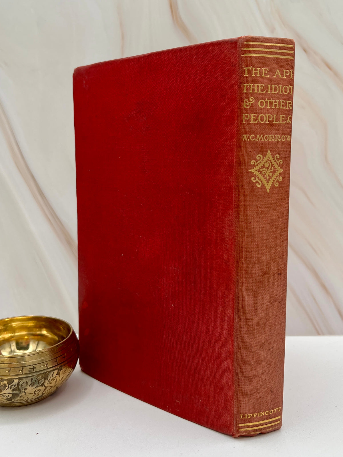 Antique red cloth hardcover book titled The Ape, the Idiot & Other People by W. C. Morrow, featuring an ornate gilt-stamped mythical dragon and gold lettering. - Photo 3