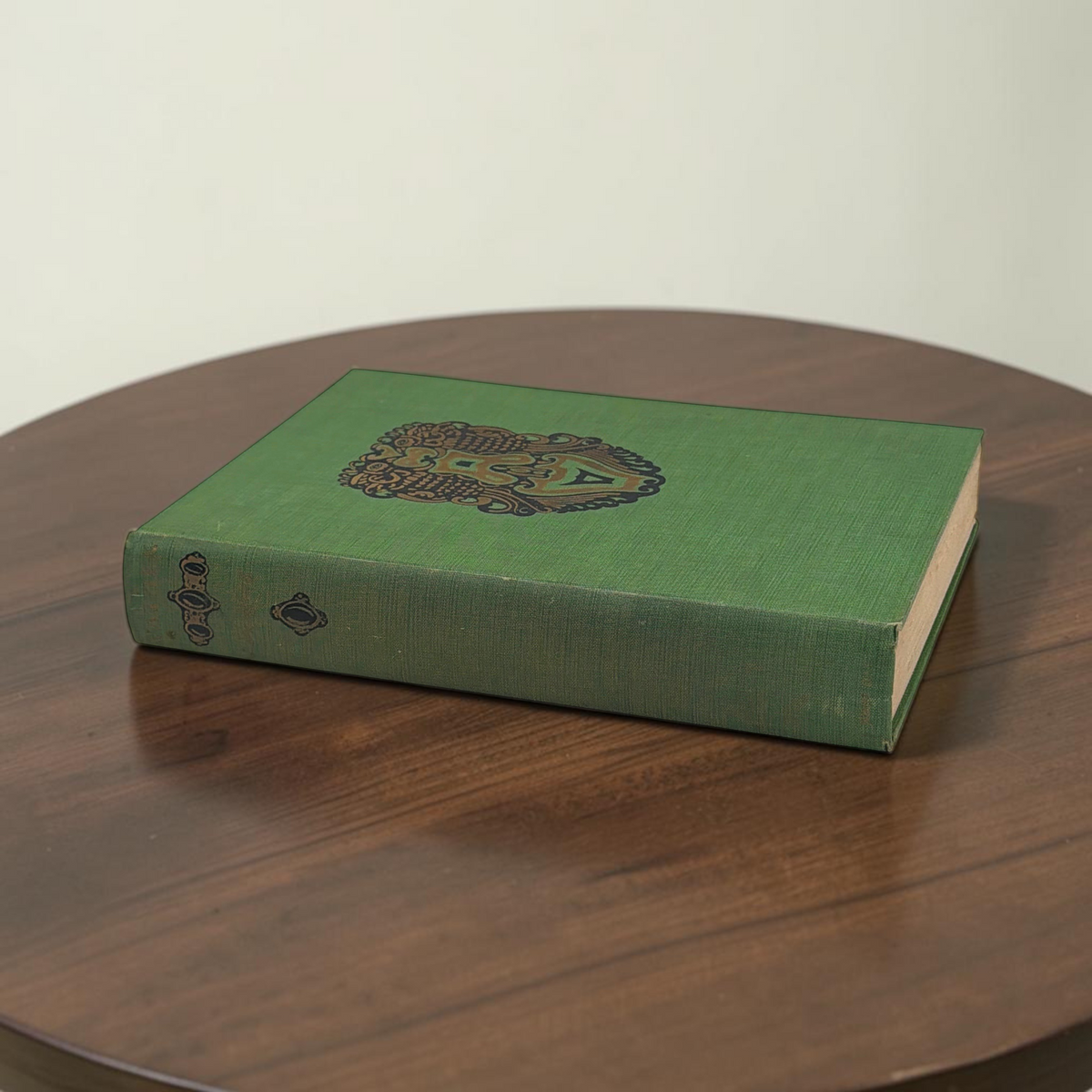 Front cover of the 1928 hardcover edition of Vathek bound in textured green book cloth, resting upright on a dark natural wood surface. - Photo 1