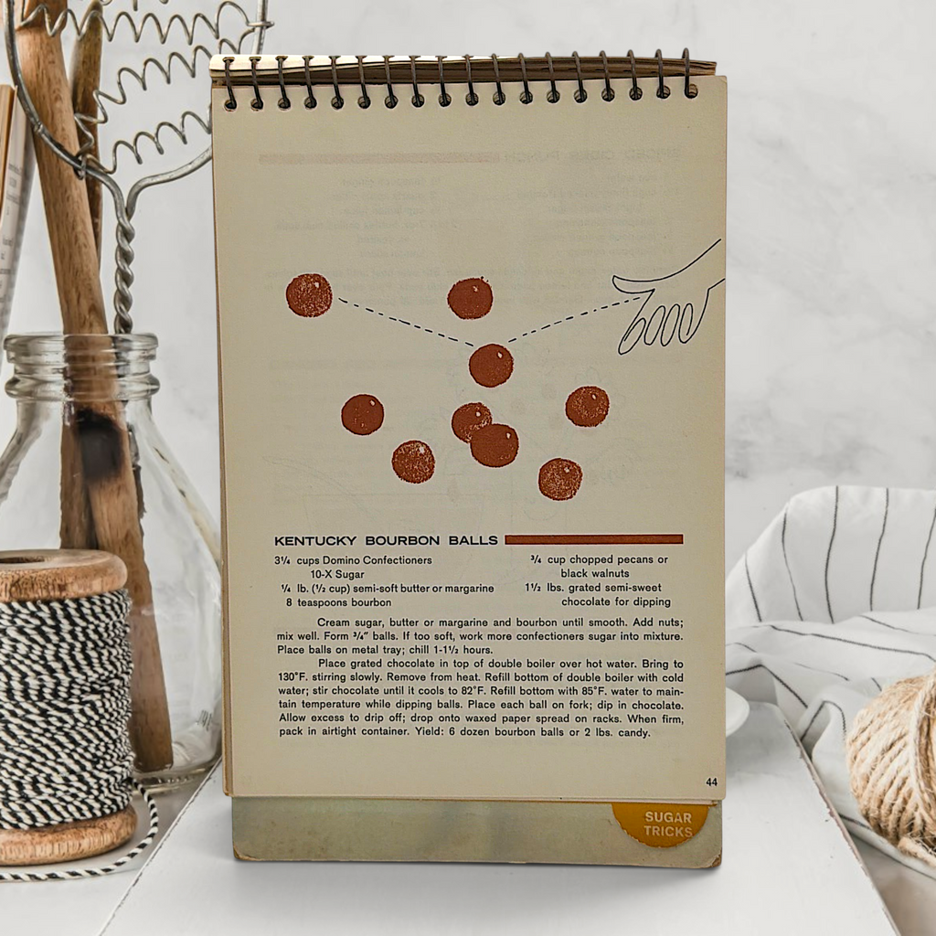 A vintage spiral-bound recipe easel stand featuring an illustration of a tiny chef piloting an antique floral sugar bowl hot air balloon over sugar dunes under a blue sky. - Photo 5