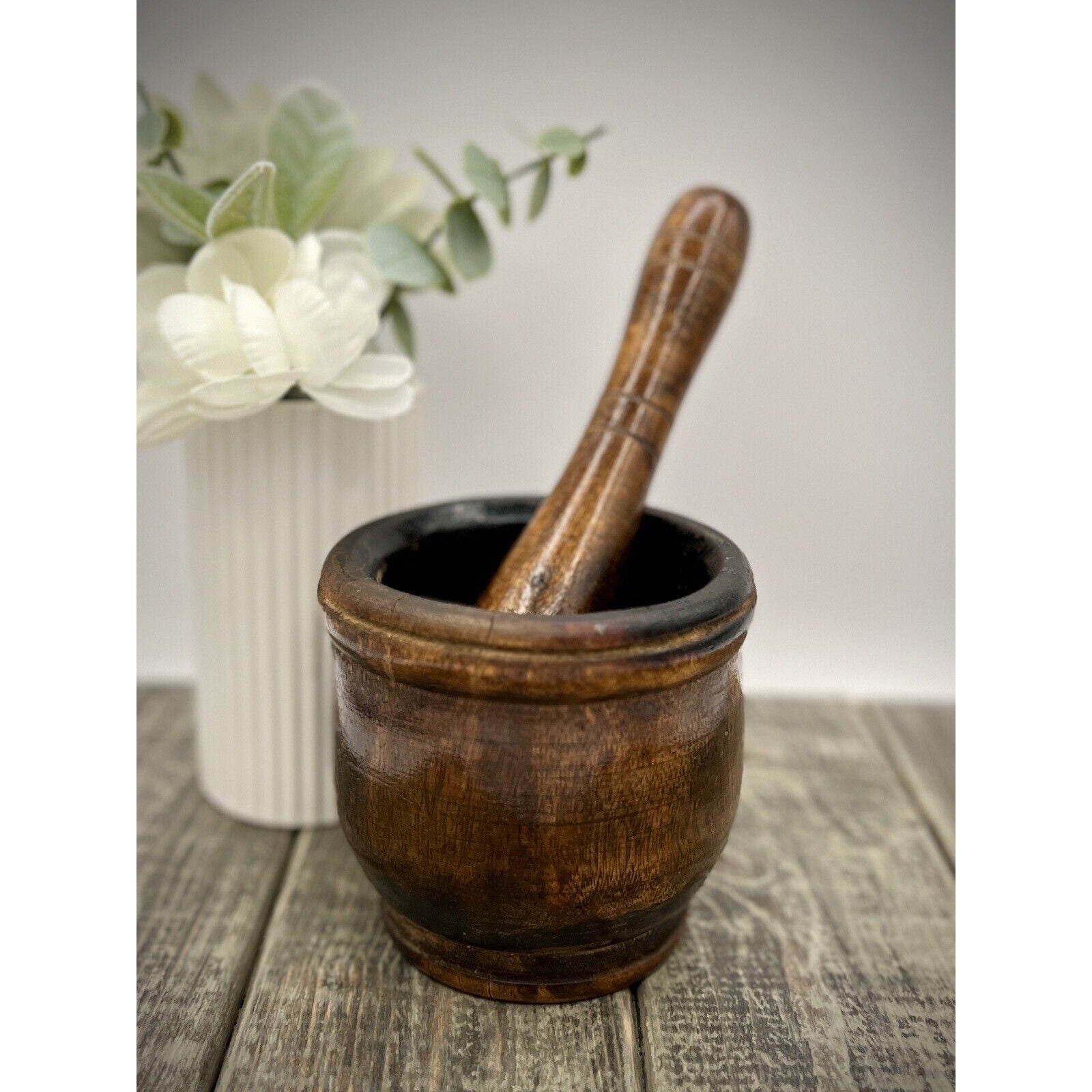 Antique wooden mortar and pestle with dark, worn patina; pestle resting inside.