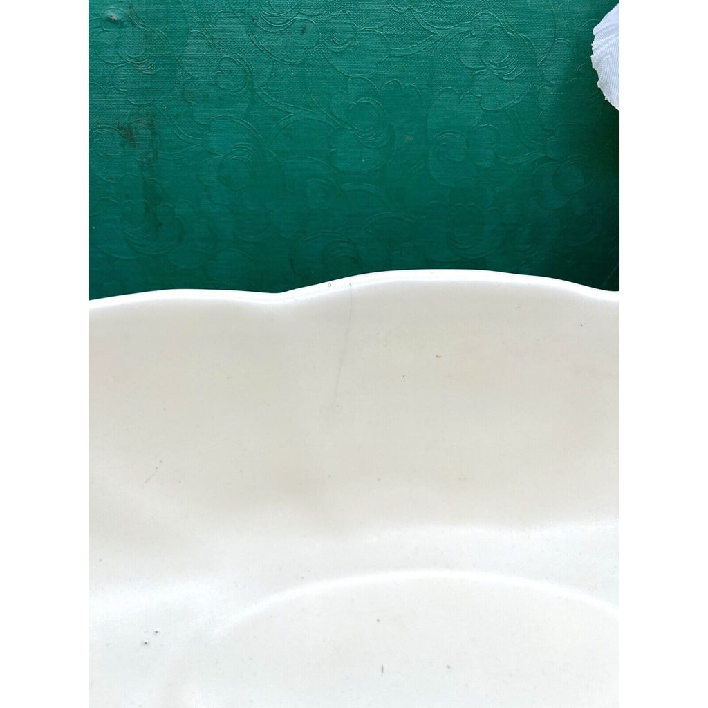 Haeger 3905 oblong ceramic bowl, white glaze with a wavy rim, edge view against green backdrop.