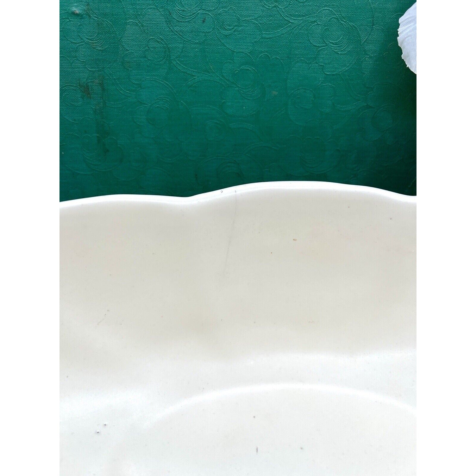 Haeger 3905 oblong ceramic bowl, white glaze with a wavy rim, edge view against green backdrop.