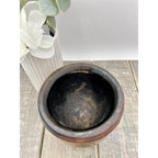 Antique dark wood mortar and pestle with worn interior on rustic wooden surface.
