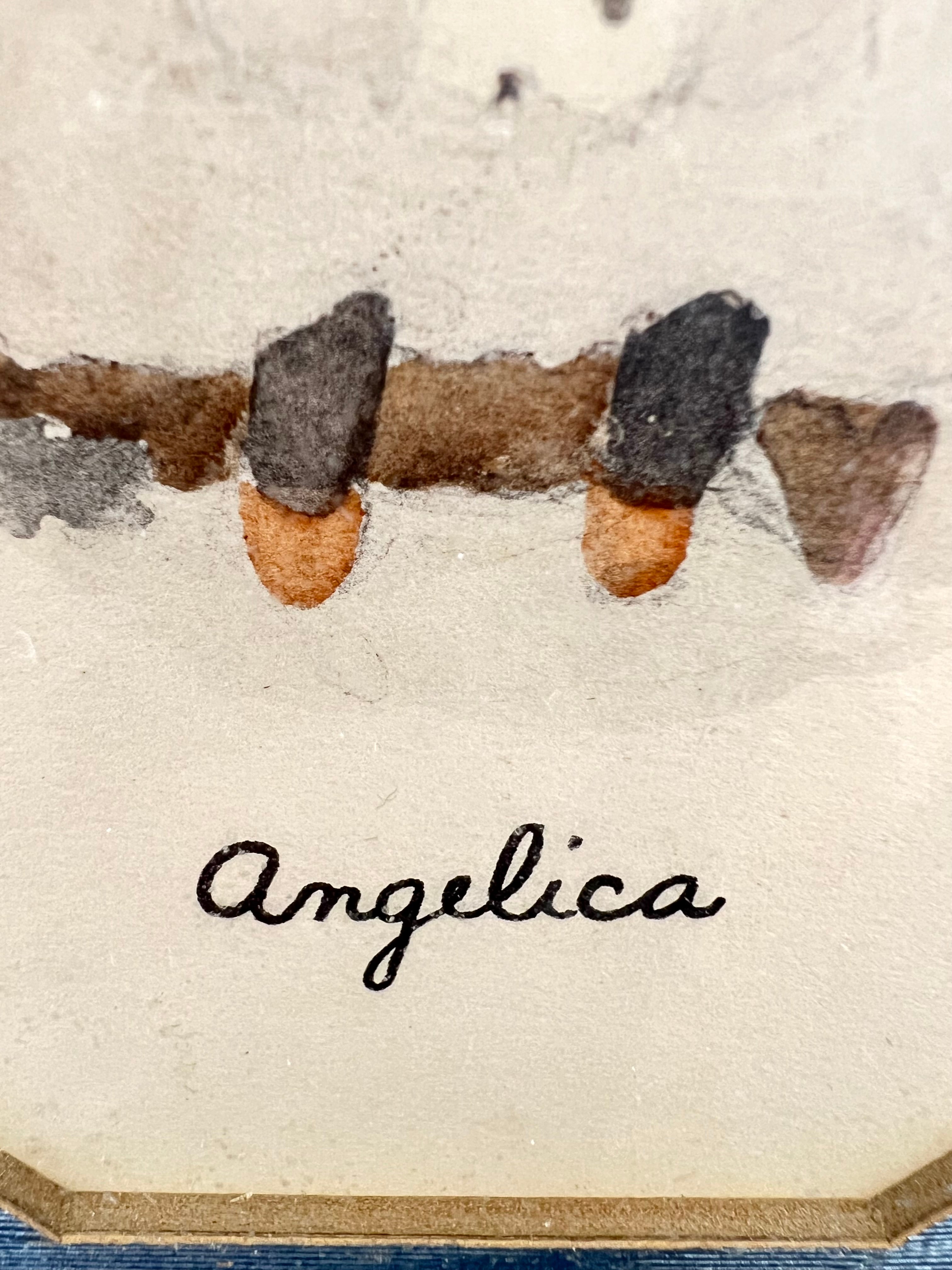 Close-up of 'Angelica' in cursive on a vintage 3.5x5.5 print with decorative border elements.