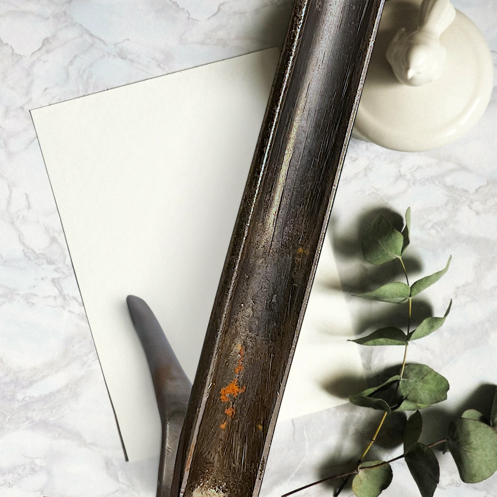 Two antique forged steel Marcel curling iron tongs with tapered points resting diagonally on white paper beside a dried eucalyptus branch. - Photo 4