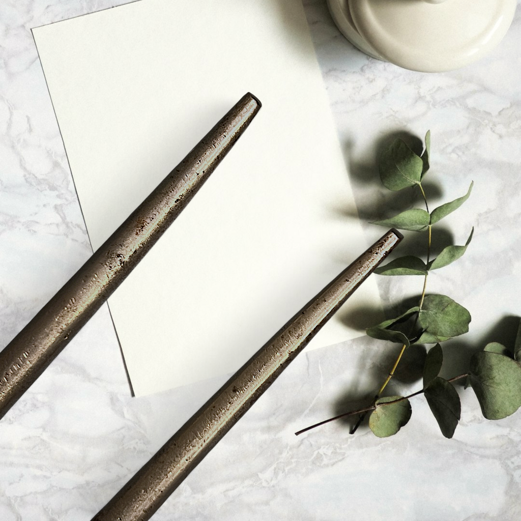 Two antique forged steel Marcel curling iron tongs with tapered points resting diagonally on white paper beside a dried eucalyptus branch. - Photo 7