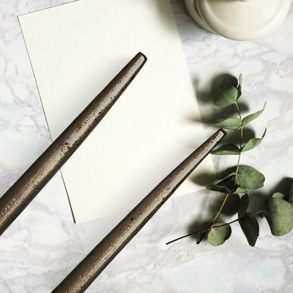 Two antique forged steel Marcel curling iron tongs with tapered points resting diagonally on white paper beside a dried eucalyptus branch. - Photo 7