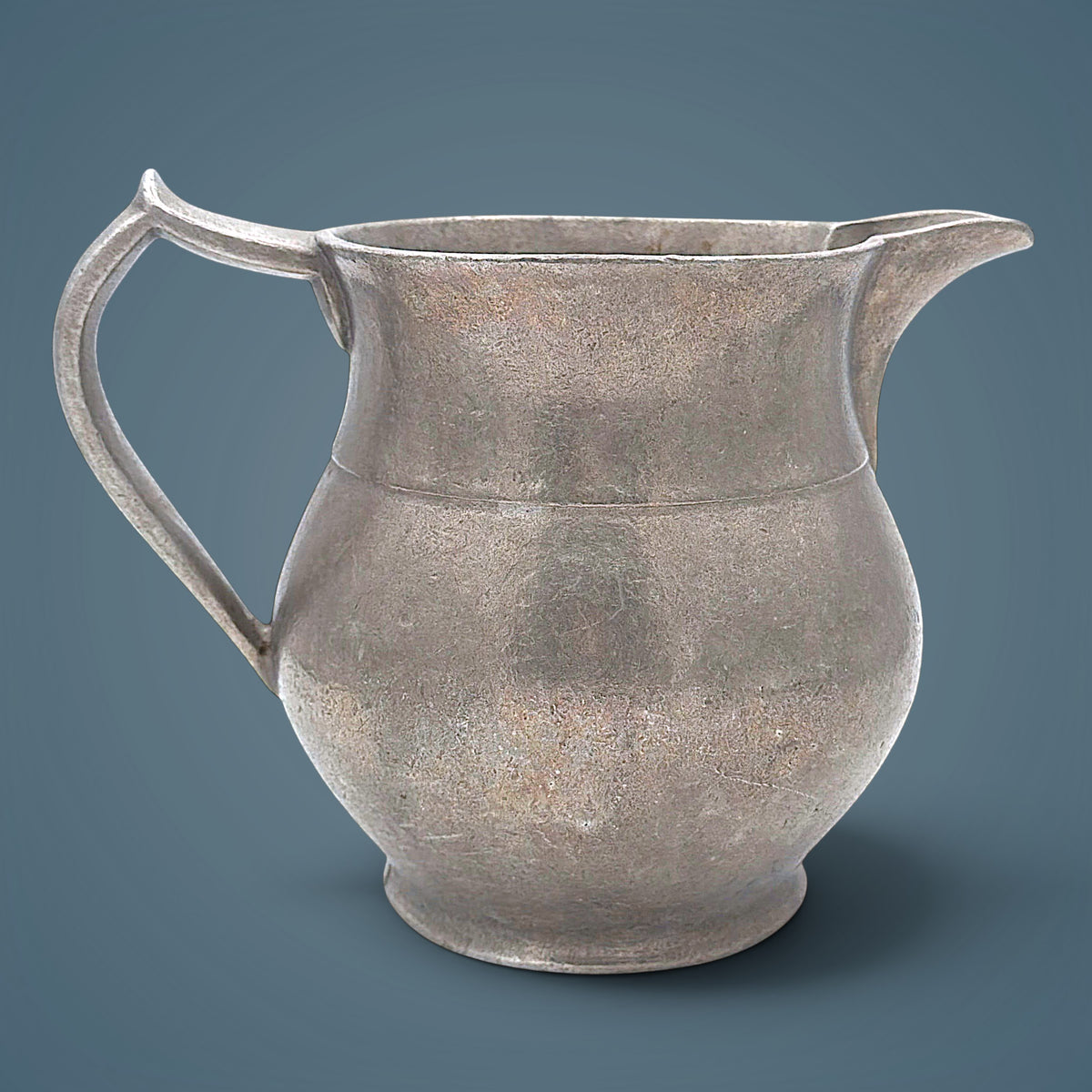 Antique pewter water pitcher in soft gray metal featuring an open flared spout, a bulbous waist with a raised decorative band, and a curved handle. - Photo 1