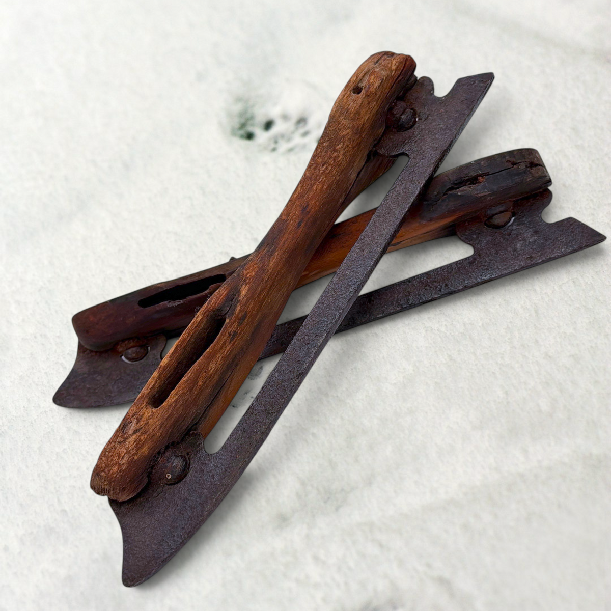 Pair of antique 19th-century hand-carved wood and wrought iron ice skates crossed on snow. - Photo 1