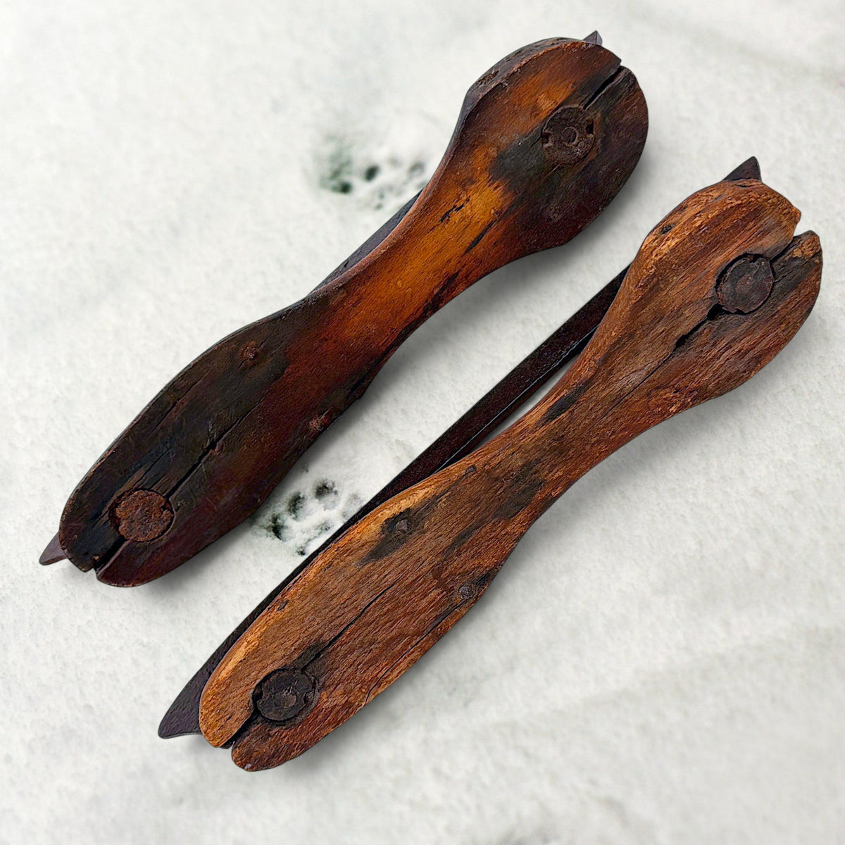 Pair of antique 19th-century hand-carved wood and wrought iron ice skates crossed on snow. - Photo 3