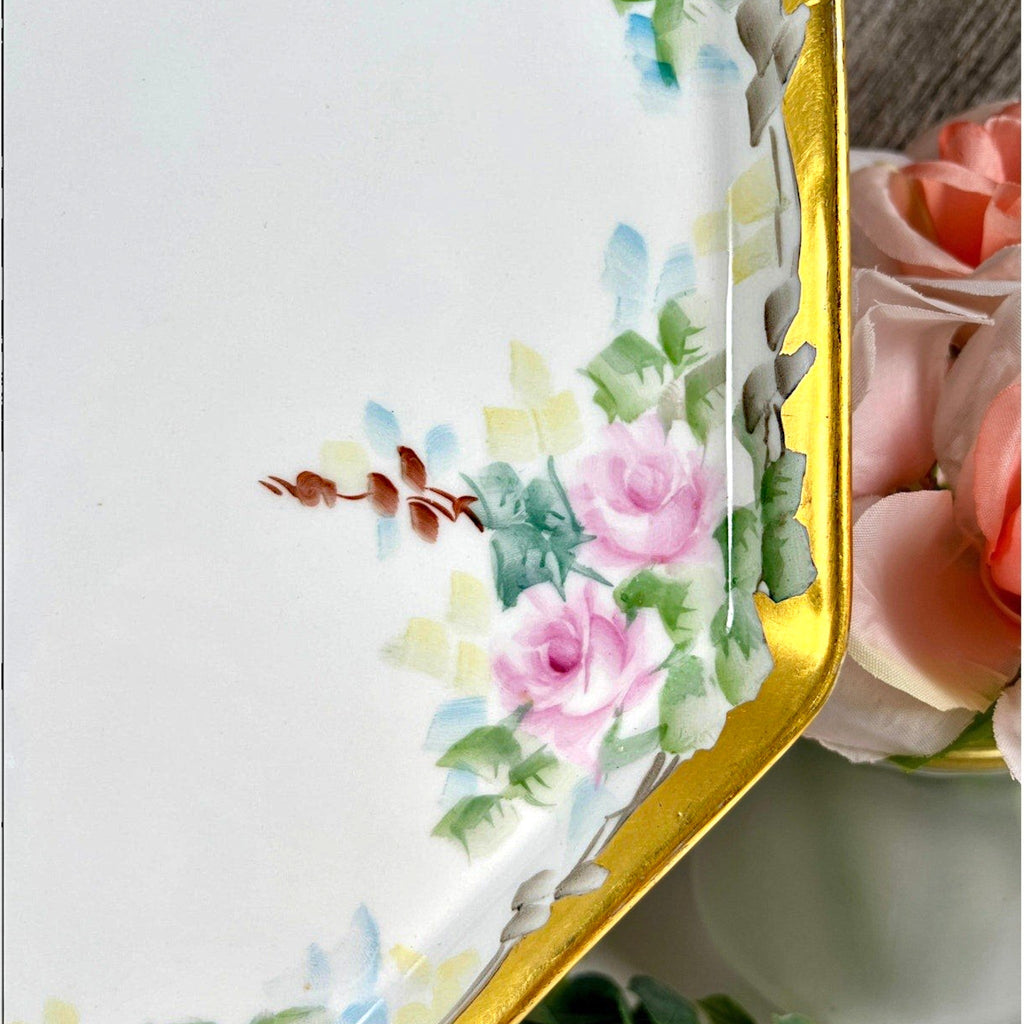 An antique white porcelain octagonal serving platter featuring a delicate gold-gilded rim, presented on a display stand among green foliage. - Photo 3