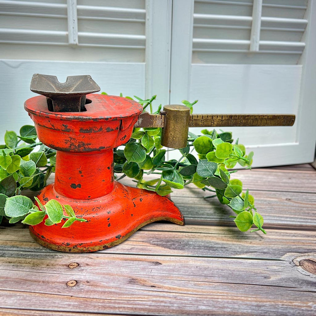 An antique Howe Scale Co. counterbalance scale with a red painted cast iron base and a graduated brass beam holding a solid cylindrical brass slider weight. - Photo 1