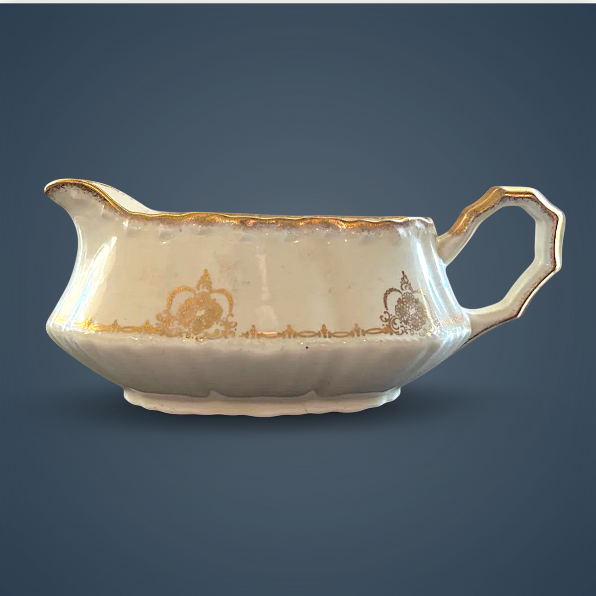 Antique white porcelain gravy boat with an embossed fluted body, scalloped gilded rim, ornate gilded handle, and gold filigree scroll accents along the base. - Photo 1