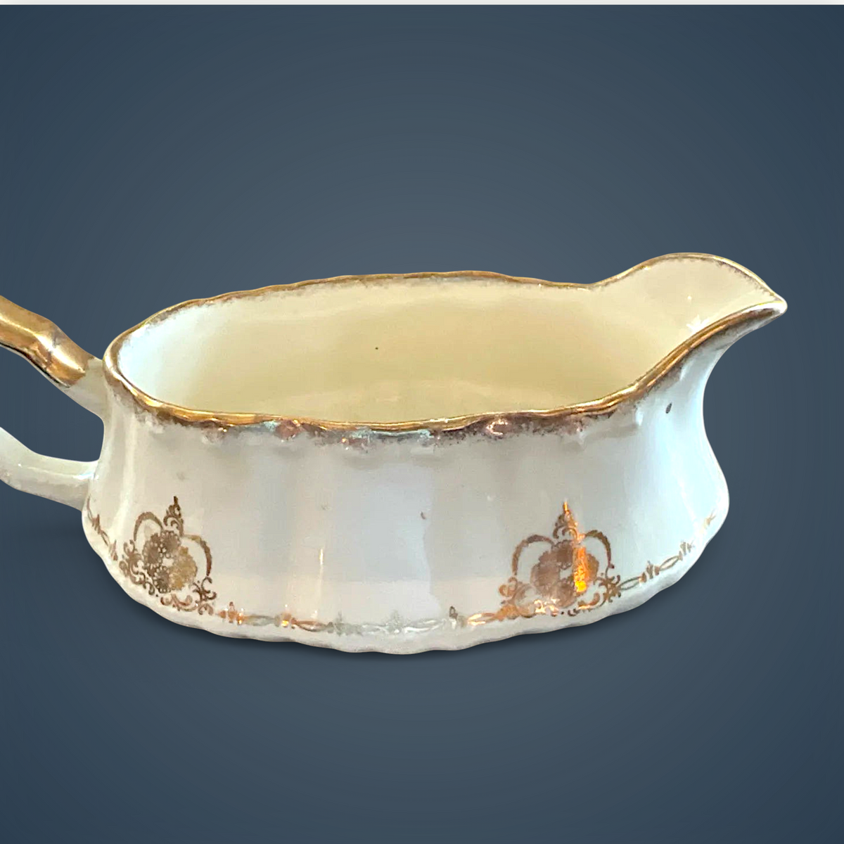 Antique white porcelain gravy boat with an embossed fluted body, scalloped gilded rim, ornate gilded handle, and gold filigree scroll accents along the base. - Photo 4