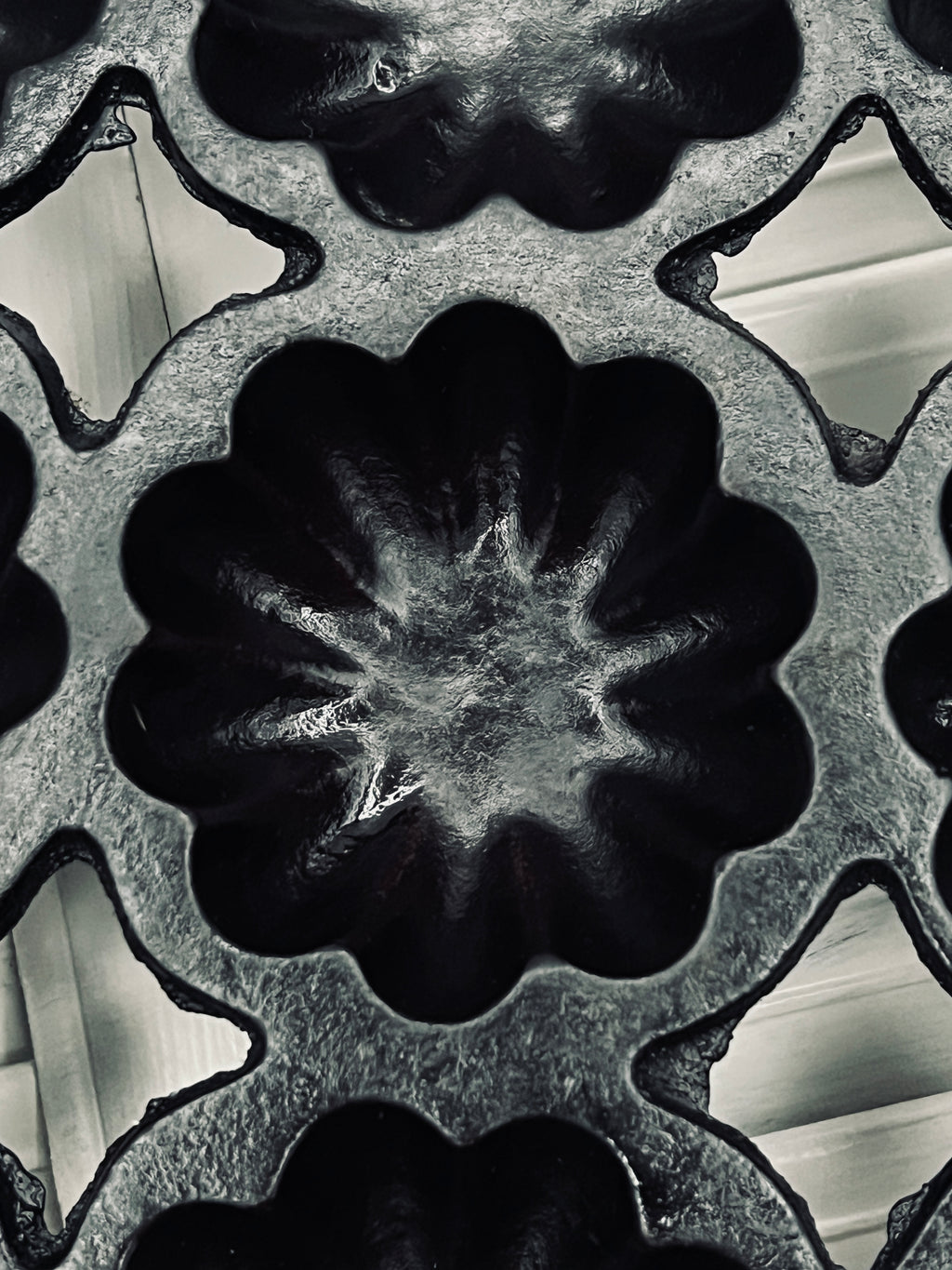 A black antique cast iron 12-cup gem pan with deeply fluted scalloped molds in a 4-4-4 open-frame layout and wavy stylized handles at both ends. - Photo 5
