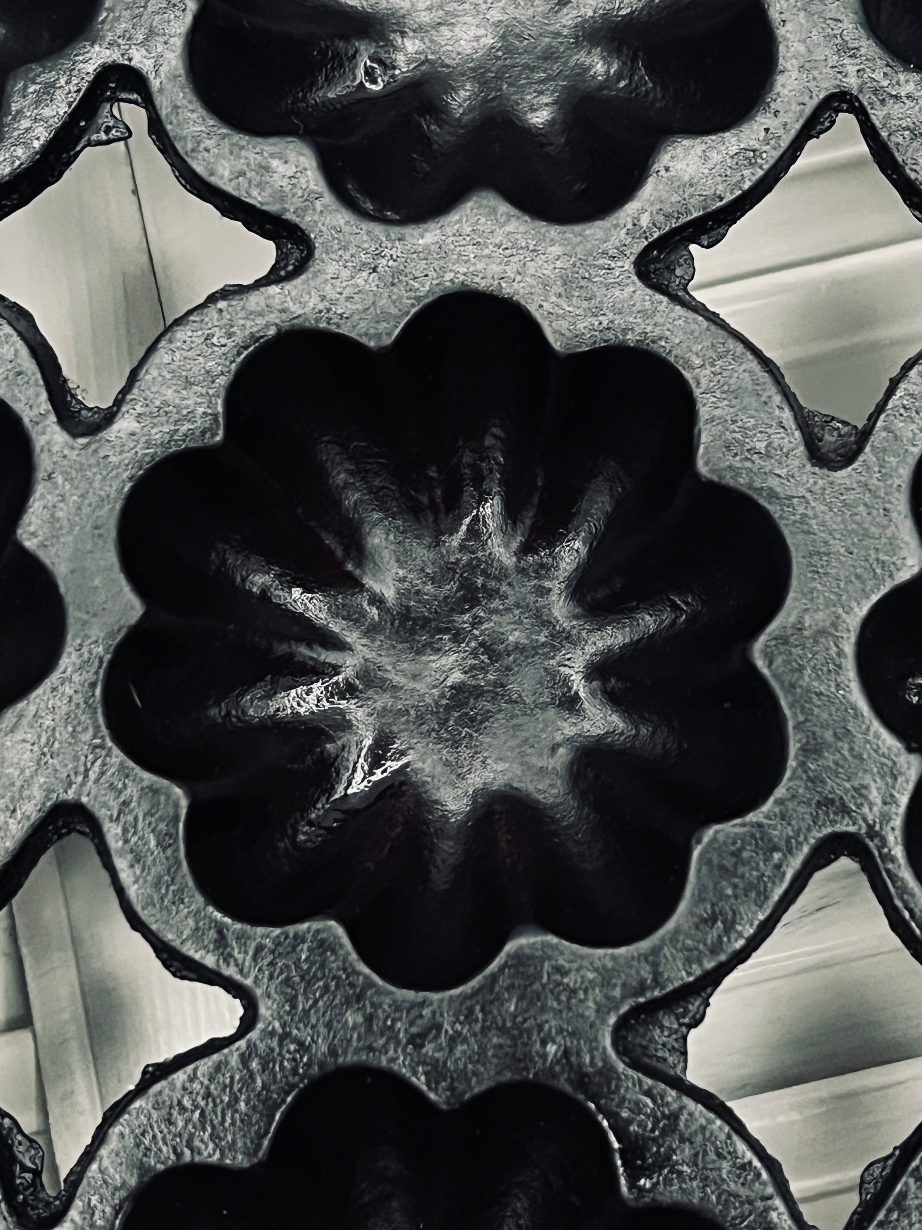 A black antique cast iron 12-cup gem pan with deeply fluted scalloped molds in a 4-4-4 open-frame layout and wavy stylized handles at both ends. - Photo 5