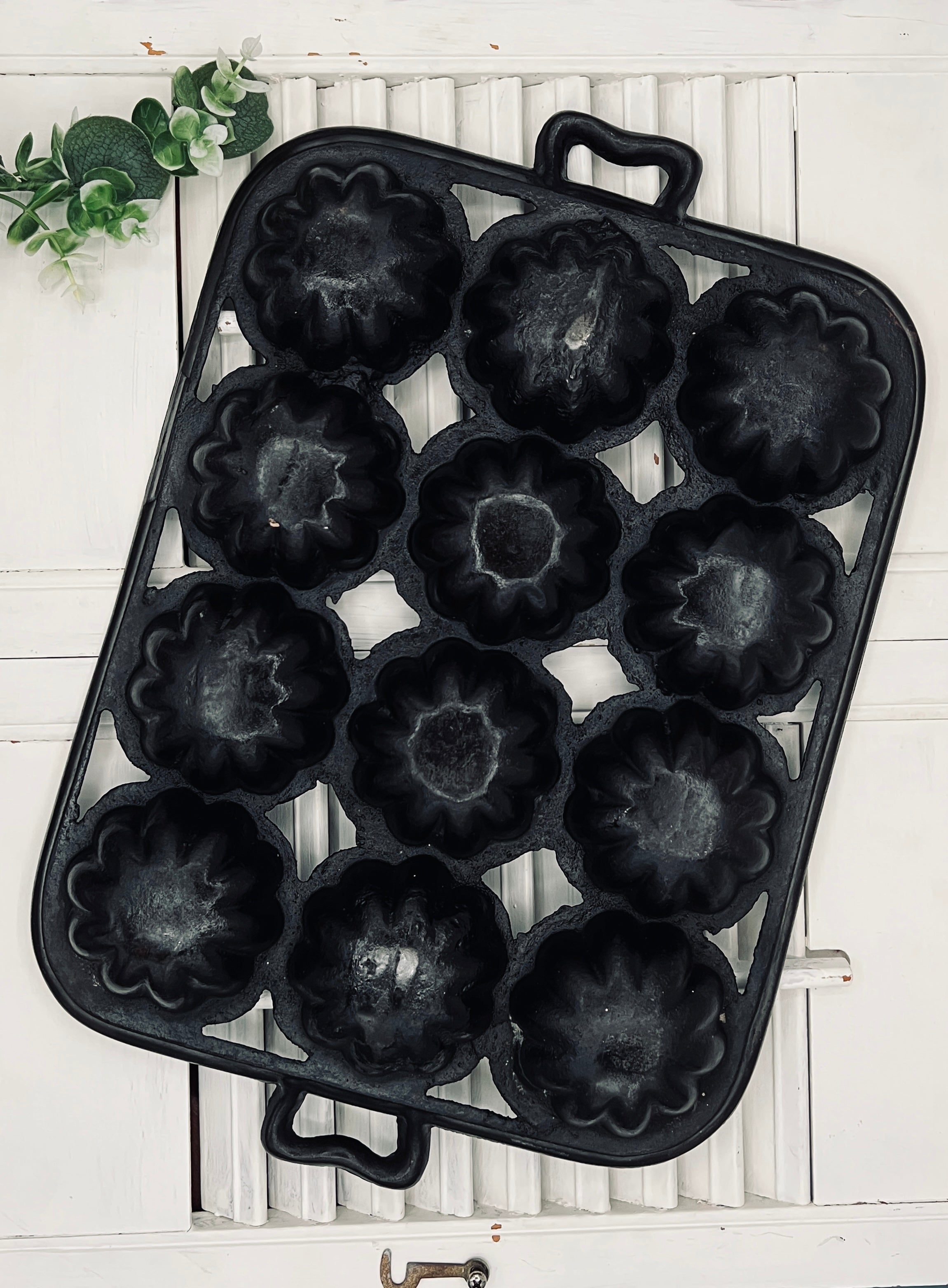 A black antique cast iron 12-cup gem pan with deeply fluted scalloped molds in a 4-4-4 open-frame layout and wavy stylized handles at both ends. - Photo 6