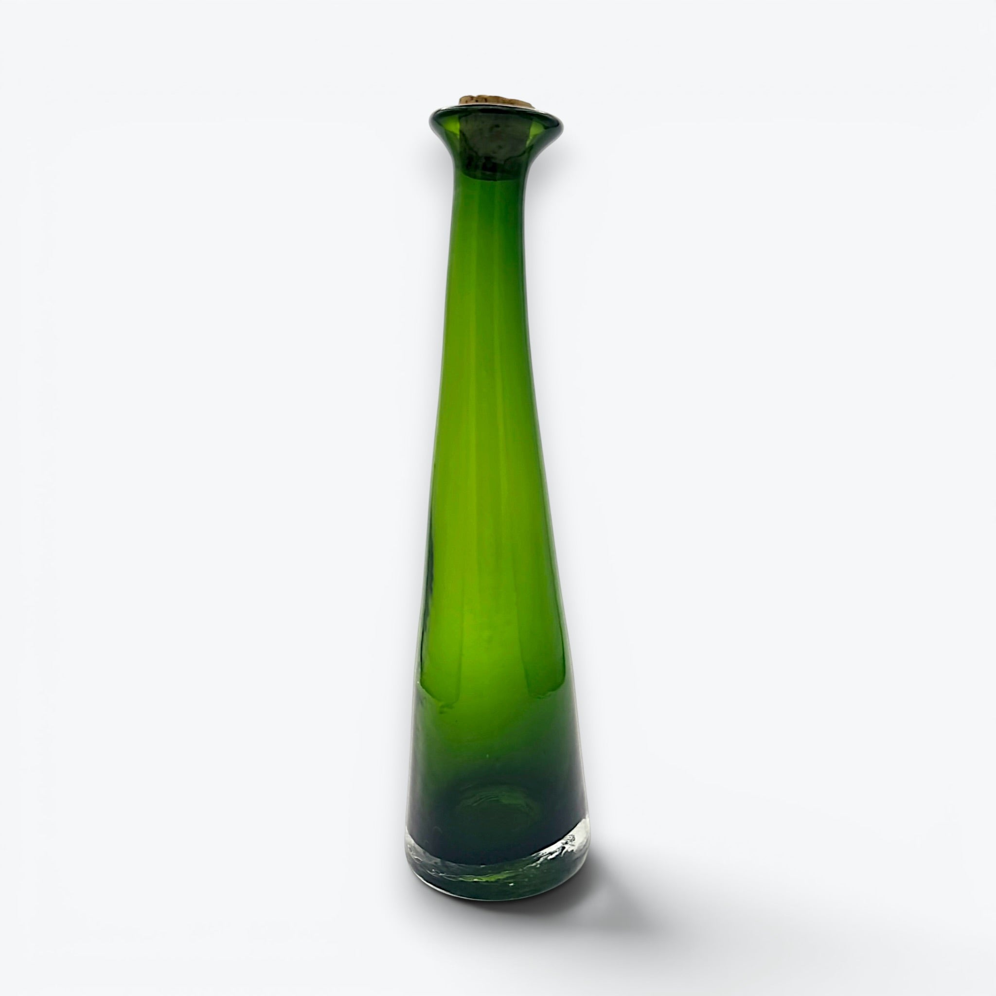 A tall, tapered mid-century green glass decanter with a flared rim and cork stopper, standing against a clean white background. - Photo 1