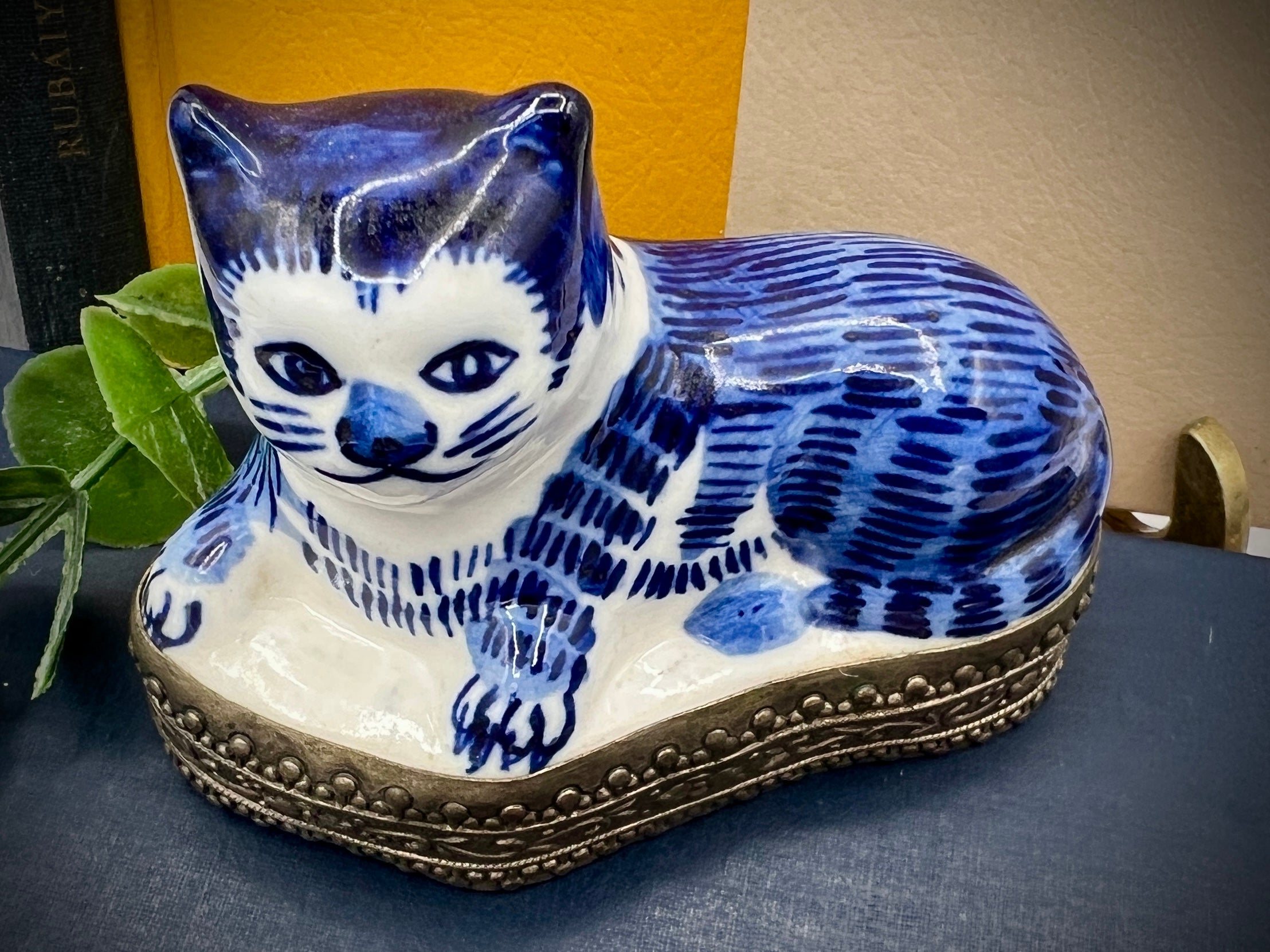 A vintage blue and white glazed porcelain cat figurine with cobalt blue painted patterns resting on an ornate embossed metal gallery base. - Photo 3