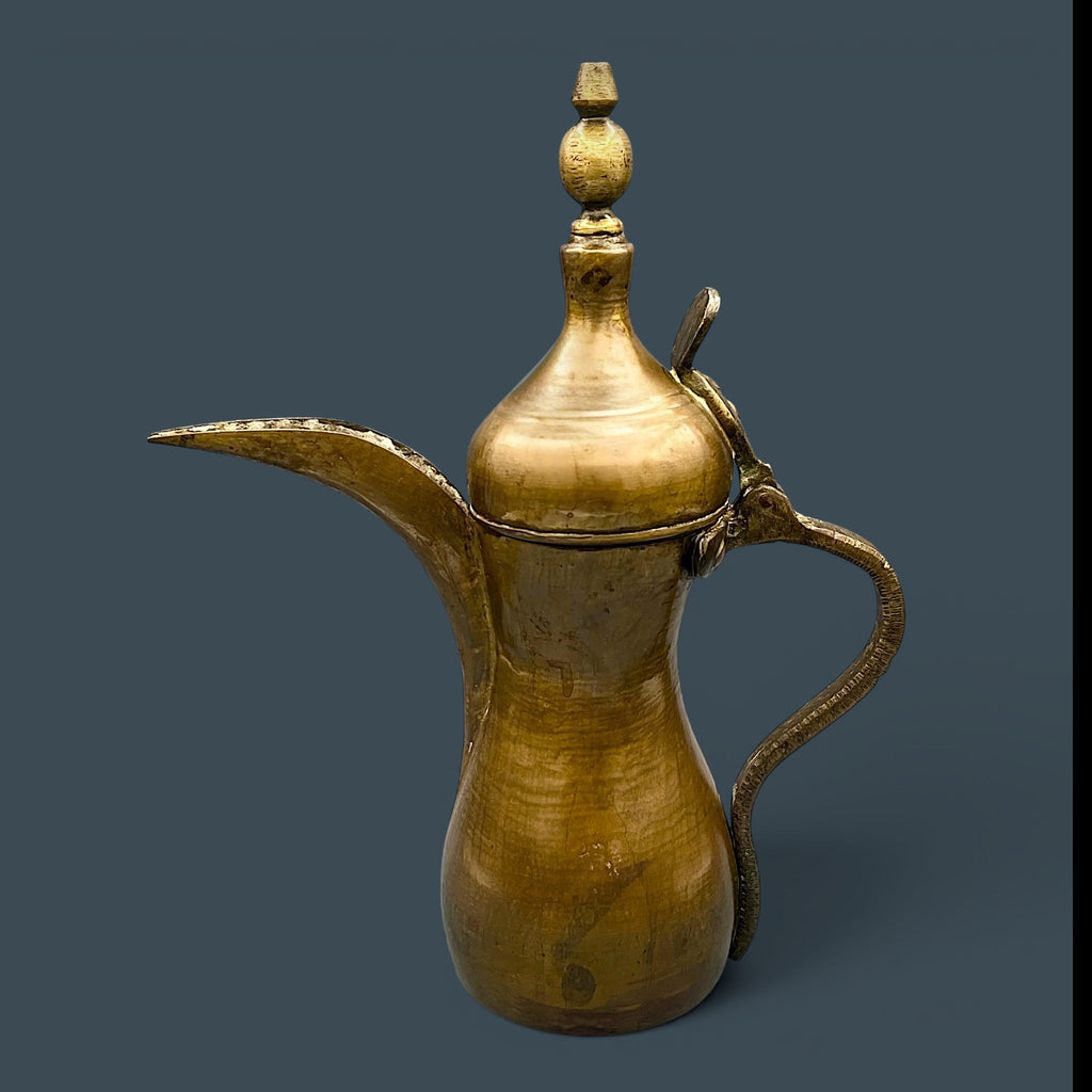An antique hand-forged brass pitcher with a tapered neck and warm golden-brown patina, displayed against a dark background. - Photo 2