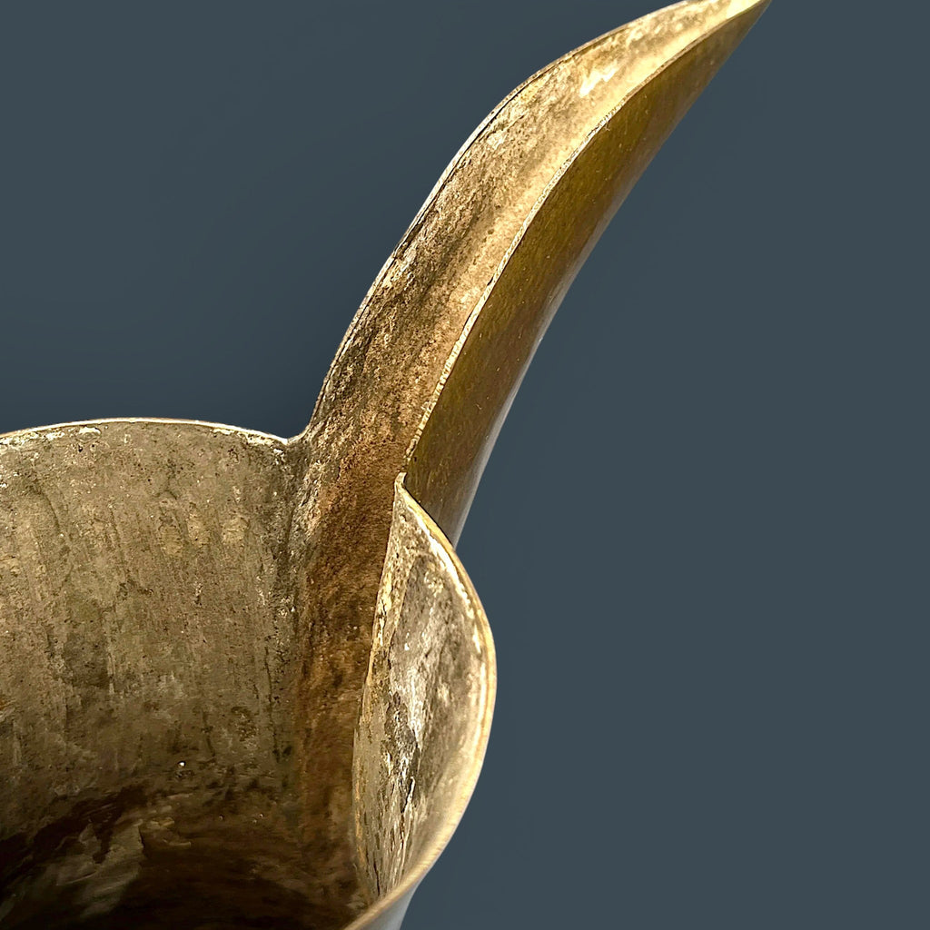 An antique hand-forged brass pitcher with a tapered neck and warm golden-brown patina, displayed against a dark background. - Photo 9