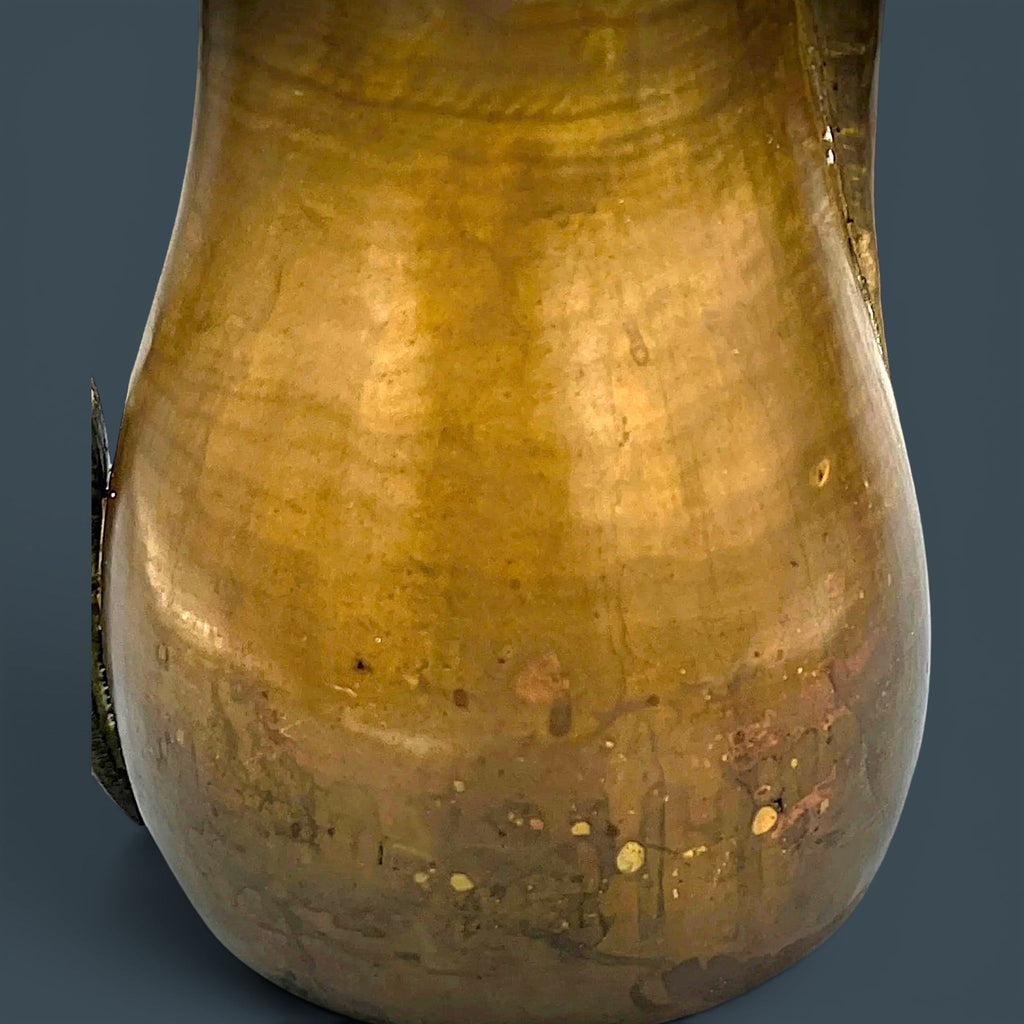 An antique hand-forged brass pitcher with a tapered neck and warm golden-brown patina, displayed against a dark background. - Photo 10
