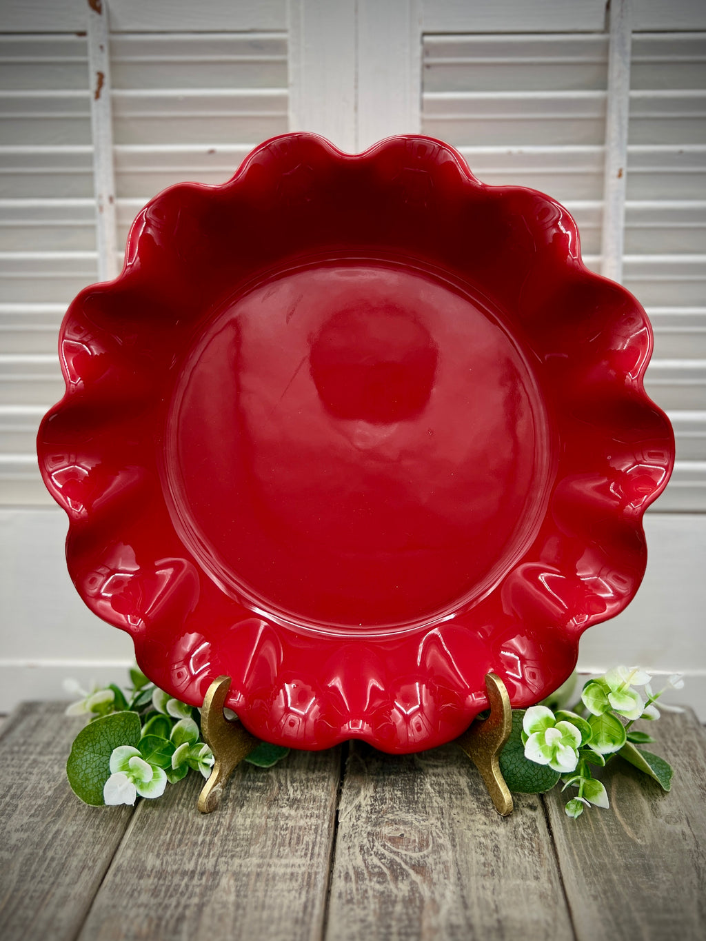 Emile Henry red ceramic deep ruffled pie dish displayed upright on a wooden surface showing its scalloped rim and glossy crimson glaze. - Photo 1