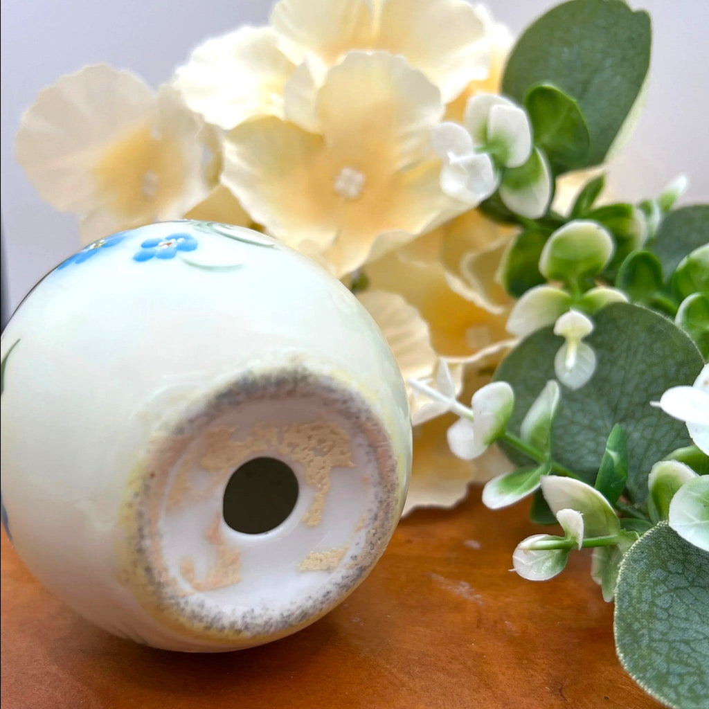 An antique porcelain egg-shaped shaker featuring hand-painted blue forget-me-not flowers along the base and heavy, lustrous gold gilding across the top, set against a background of cream flowers and green foliage. - Photo 5