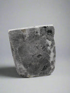 Bottom of stone statue with a textured surface on a white background
