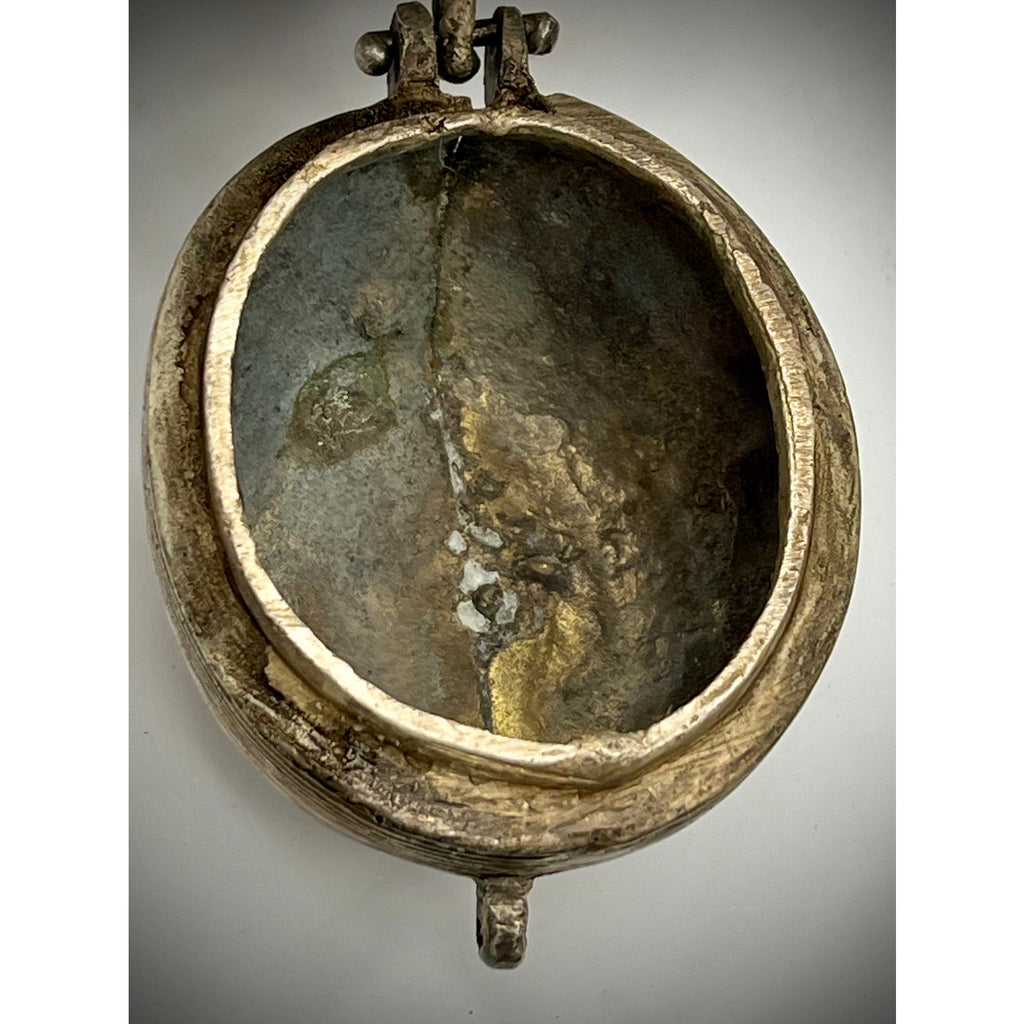 Bronze or similar metal trinket box with a reflective surface on a gray background