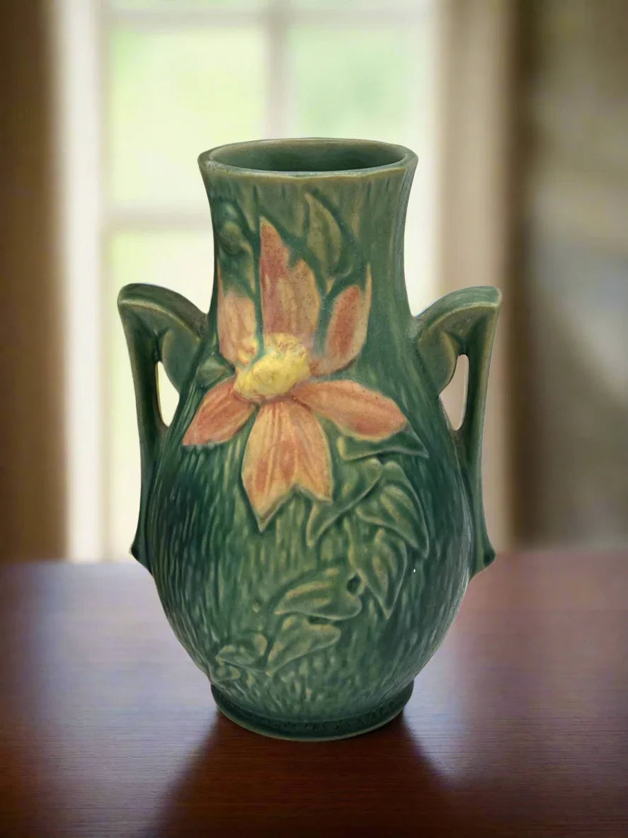 Vintage Roseville Clematis art pottery vase featuring an earthy green textured ground, sculpted angular side handles, and an embossed peach clematis bloom with a yellow center. - Photo 1