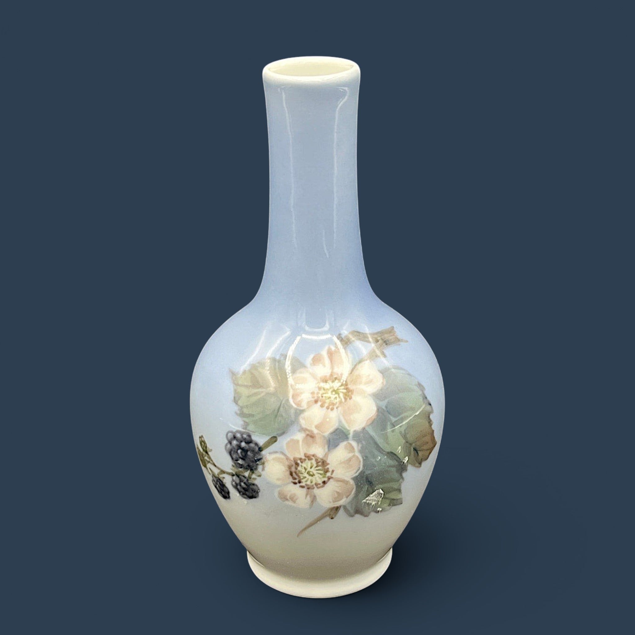 A Royal Copenhagen porcelain bud vase featuring a bulbous body, a slender elongated neck, and a glossy white glaze that fades into a soft cream and pale blue-gray gradient at the base. - Photo 1