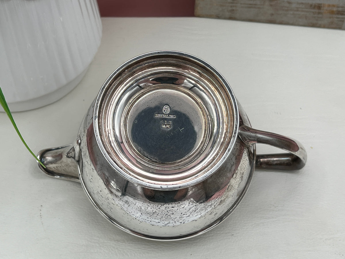 Antique William B. Durgin sterling silver two-handled covered sugar bowl with a polished urn-shaped body, stepped pedestal base, and matching domed lid topped with an urn finial displayed on a white tabletop. - Photo 9