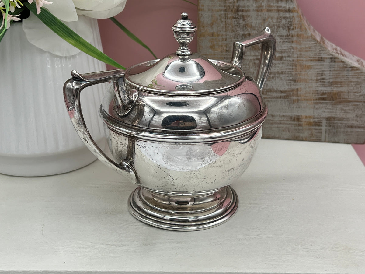 Antique William B. Durgin sterling silver two-handled covered sugar bowl with a polished urn-shaped body, stepped pedestal base, and matching domed lid topped with an urn finial displayed on a white tabletop. - Photo 12