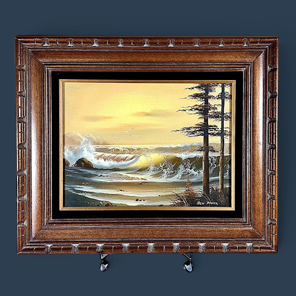 A vintage oil on canvas seascape painting depicting a sunset ocean with waves and coastal pine trees in the foreground, signed by artist Ben Power and housed in a deep wood frame with a black velvet mat. - Photo 1