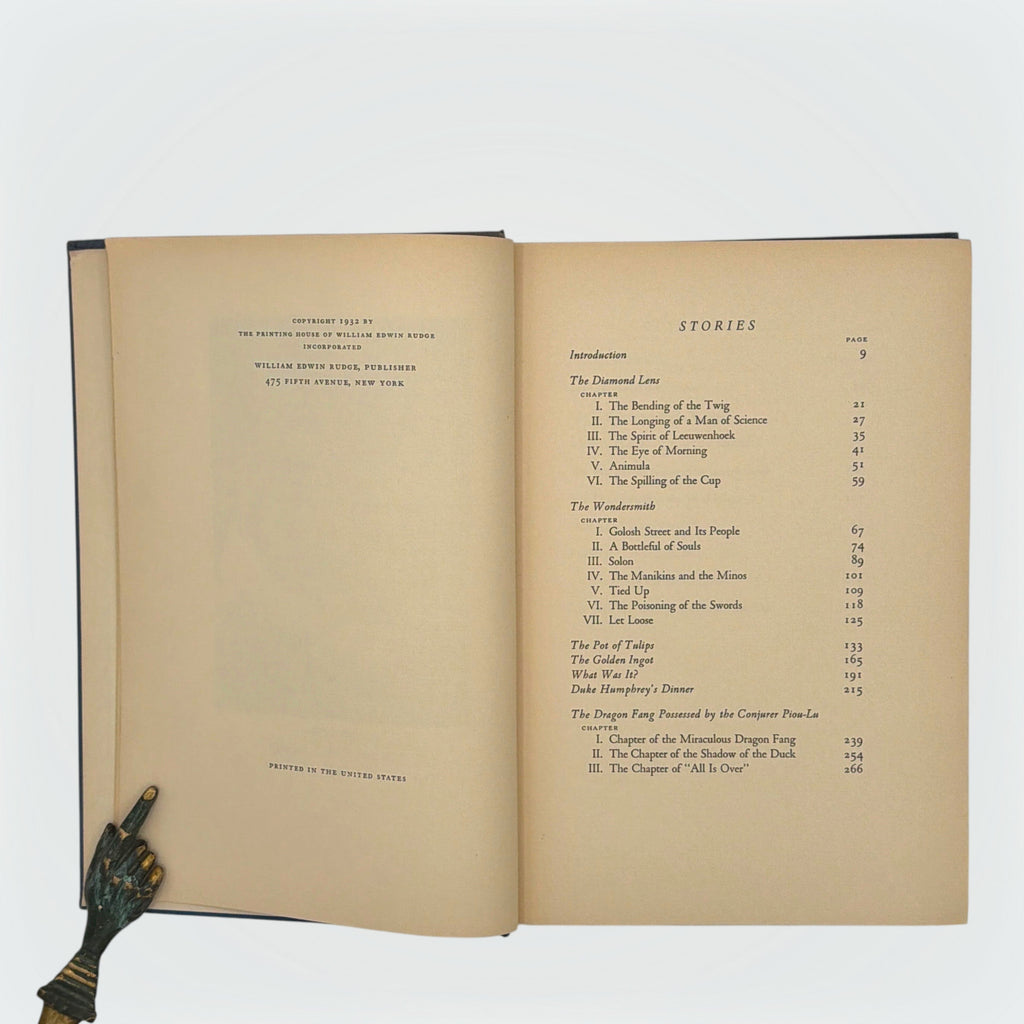 Open hardcover volume of The Diamond Lens and Other Stories displaying the printed colophon leaf set in Estienne type on cream paper with dark blue cloth covers. - Photo 4
