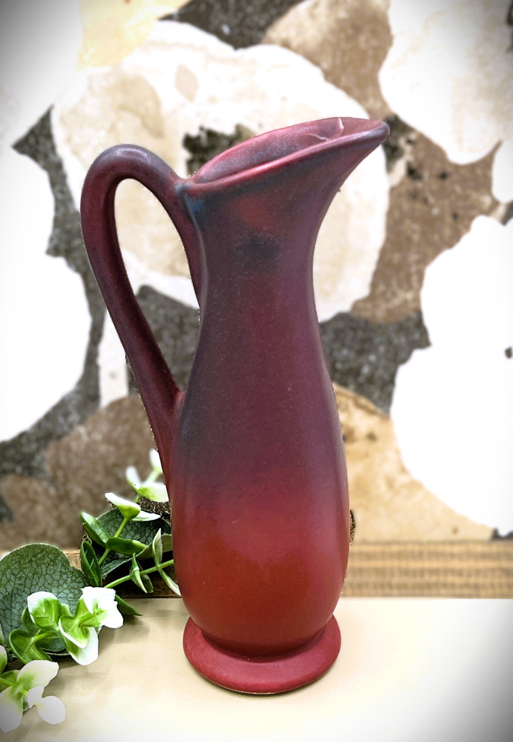 A vintage Van Briggle ceramic pitcher featuring a deep mulberry matte glaze with soft blue-tinted highlights along the pinched spout and sculpted arched handle. - Photo 1