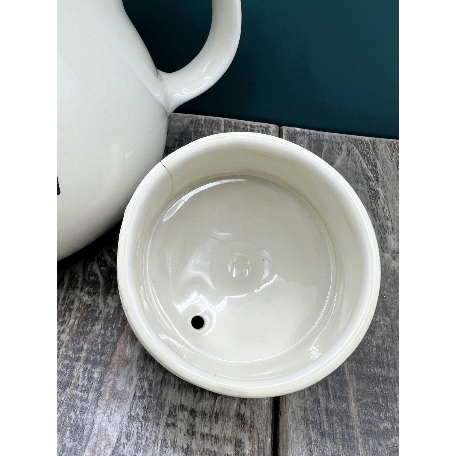 A warm cream ceramic teapot with a black silhouette tavern scene decal, showcasing a classic Art Deco streamlined design and platinum luster accents on the sweeping handle and spout. - Photo 6