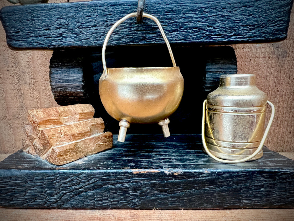 A vintage miniature fireplace hearth crafted from dark wood, showcasing tiny split logs and a gold-colored brass cauldron pot with a thin metal handle. - Photo 3