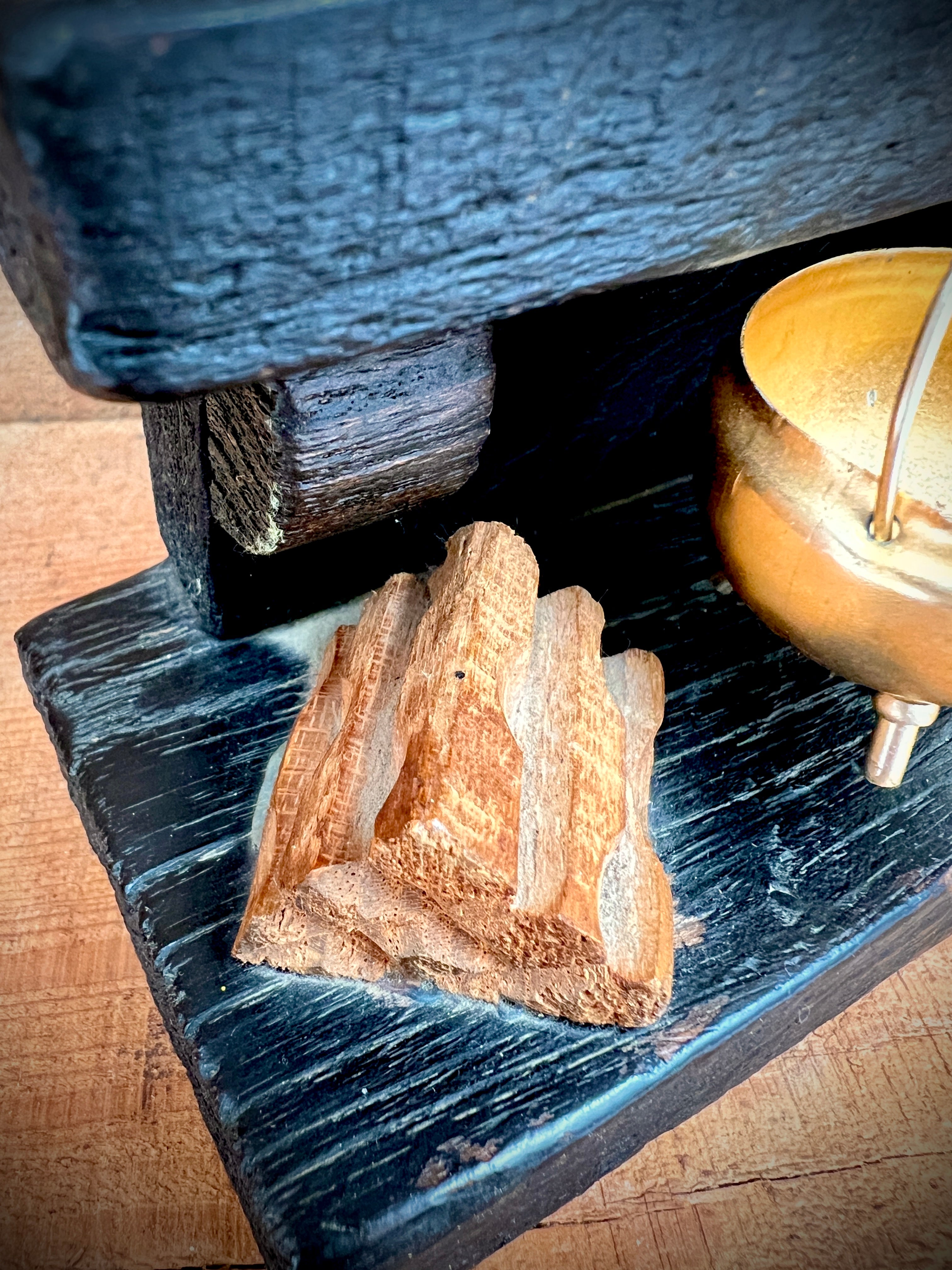A vintage miniature fireplace hearth crafted from dark wood, showcasing tiny split logs and a gold-colored brass cauldron pot with a thin metal handle. - Photo 5