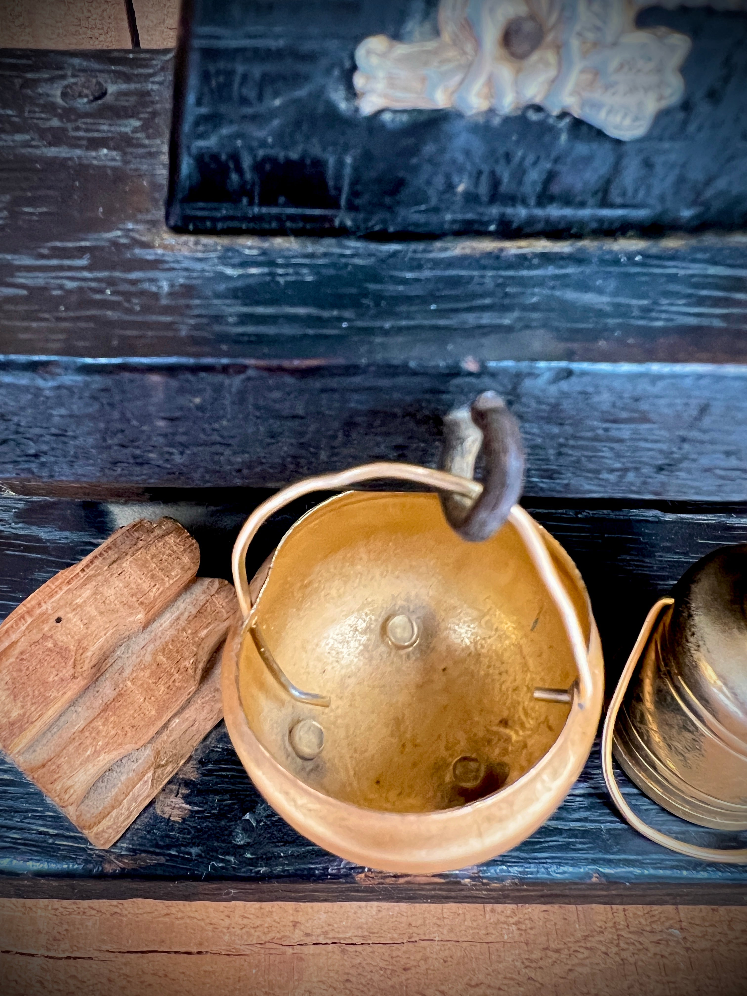 A vintage miniature fireplace hearth crafted from dark wood, showcasing tiny split logs and a gold-colored brass cauldron pot with a thin metal handle. - Photo 7