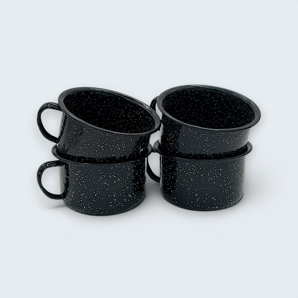 A vintage black enamel cup with white speckles and a single handle, showing a rustic interior with character-building wear at the bottom. - Photo 1